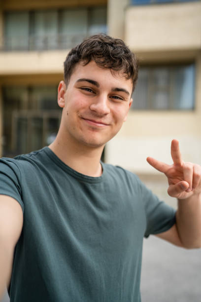 One man young adult caucasian teenager stand outdoor posing self portrait selfie looking to the camera happy confident wear shirt casual real person copy space ugc user generated content